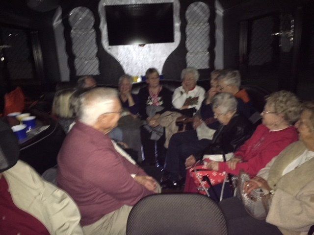 A group of people are sitting in a dark room in front of a television