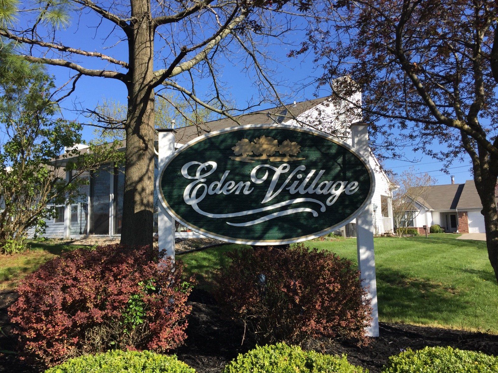 A sign for eden village is in front of a house