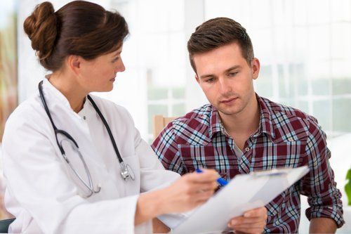 A doctor is talking to a patient who is looking at a clipboard.
