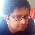 A close up of a man wearing glasses and a black shirt.