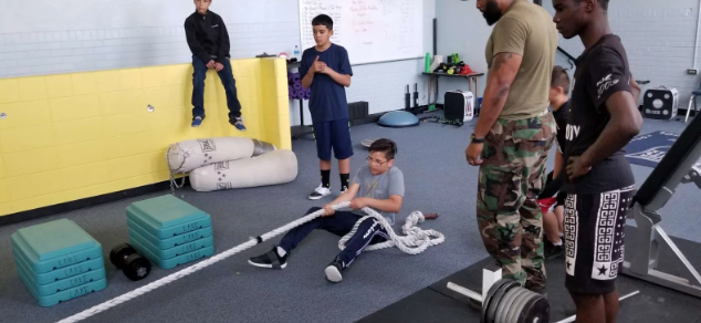 A group of young boys are playing with a rope in a gym.
