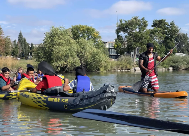 A group of people are rowing kayaks on a river.