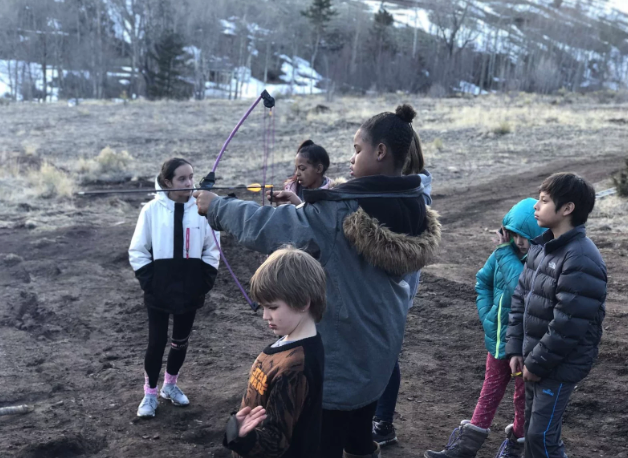 A group of children are playing with a kite in a field.