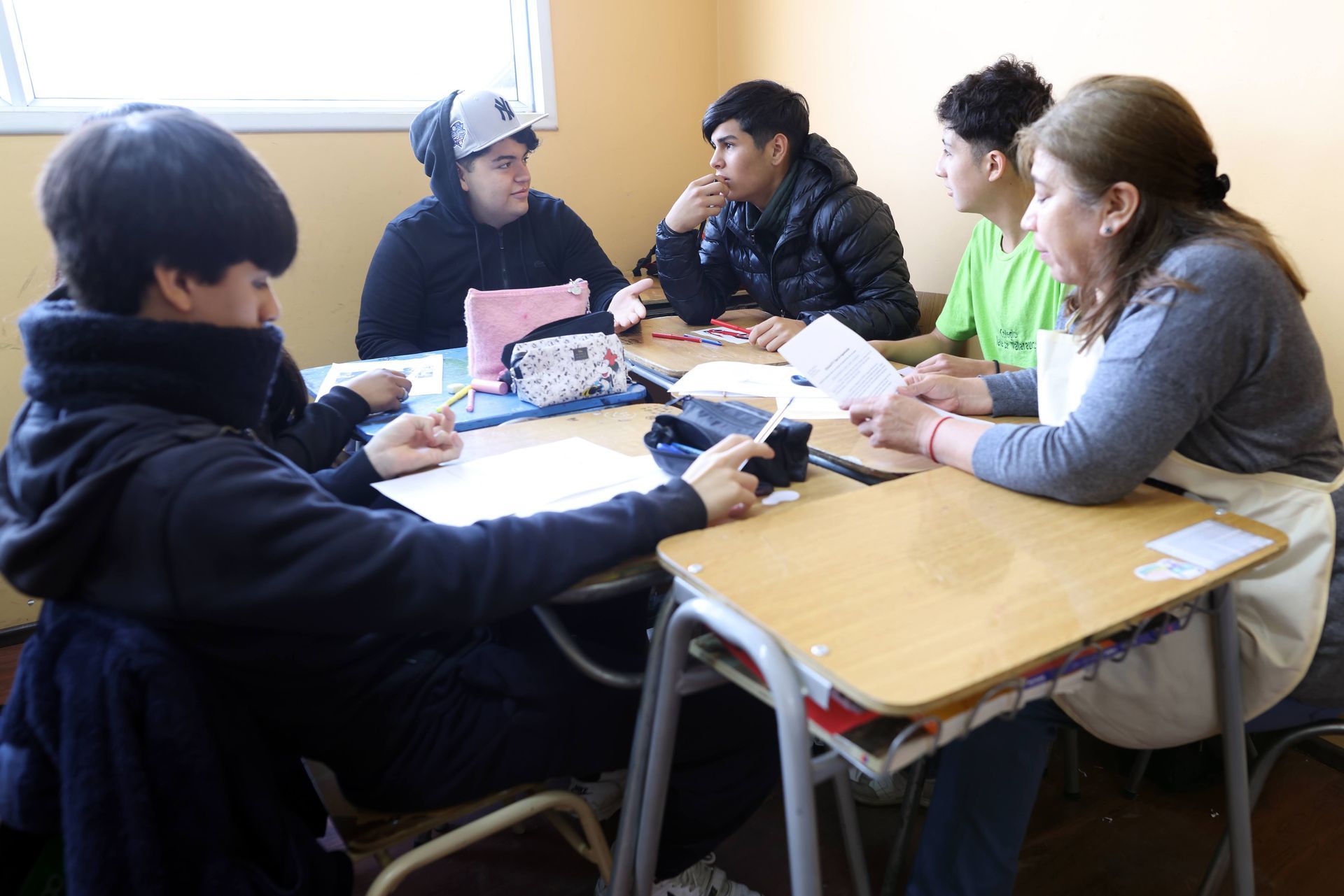 Dos niños se columpian en un columpio de neumático al aire libre; uno sonríe a la cámara, sujetando la cadena.