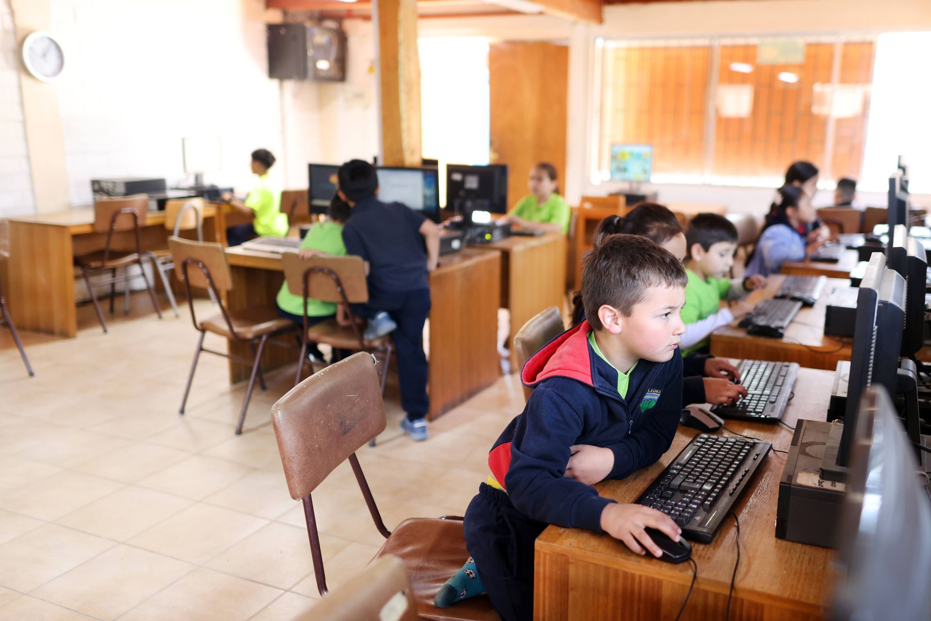 Cuatro estudiantes posan al aire libre cerca de las escaleras de la escuela, vistiendo sudaderas azul marino.