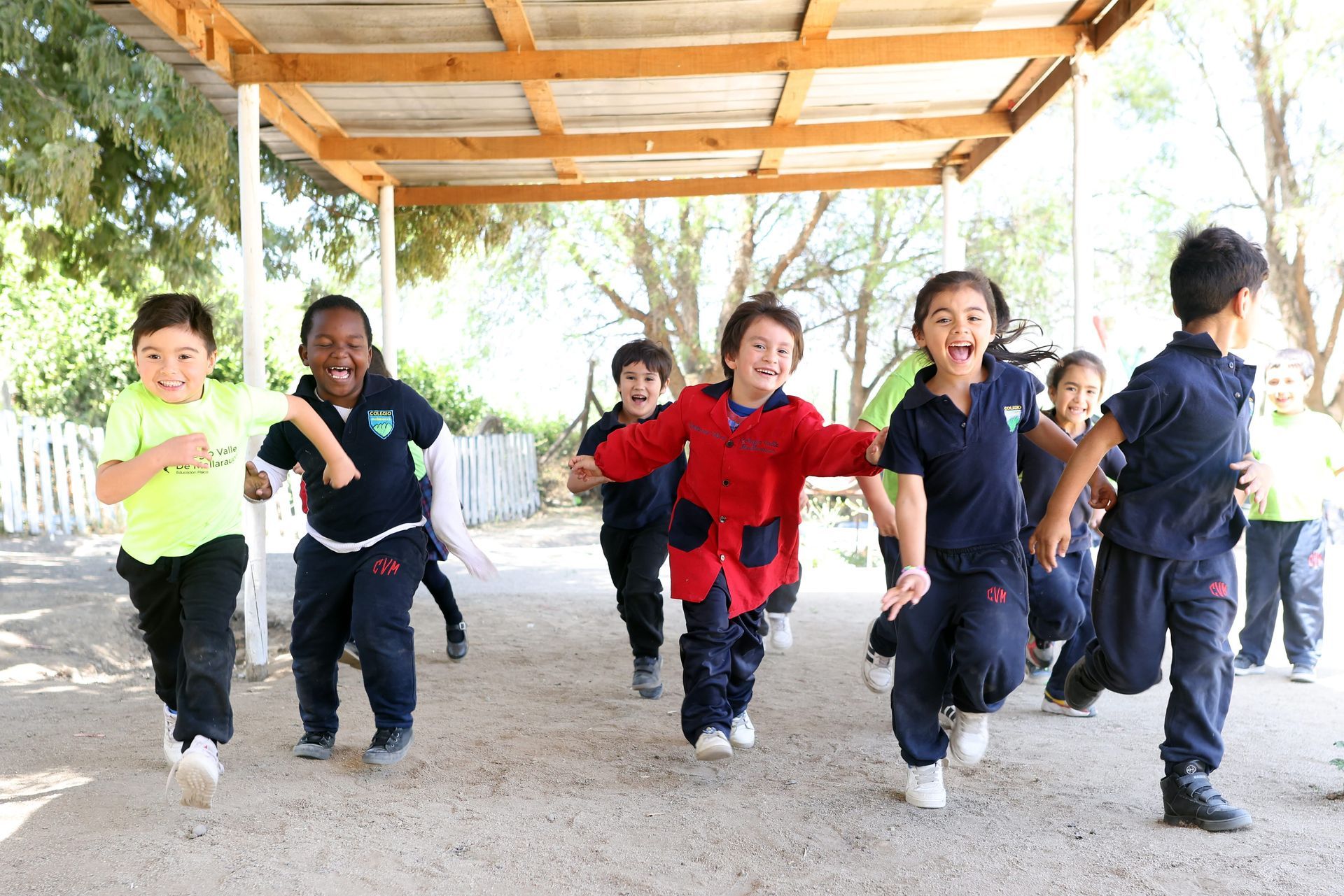 Tres niños sentados a una mesa con tazas y bocadillos, sonriendo a la cámara.