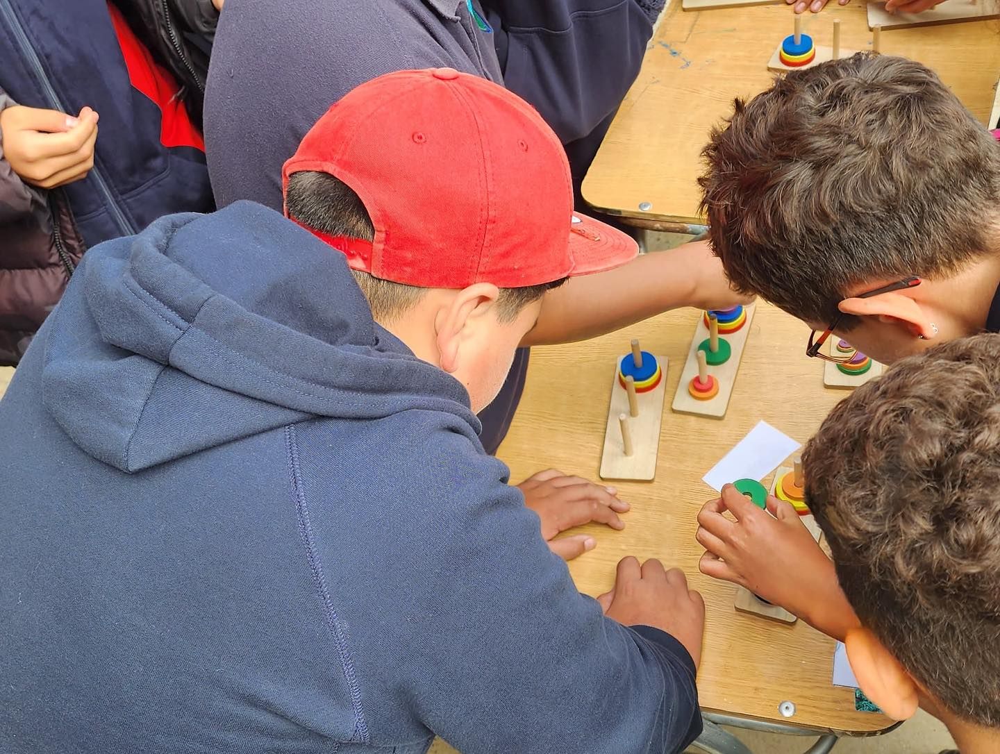Niños jugando a un juego de clasificación por colores sobre una mesa, con discos azules, rojos y amarillos.
