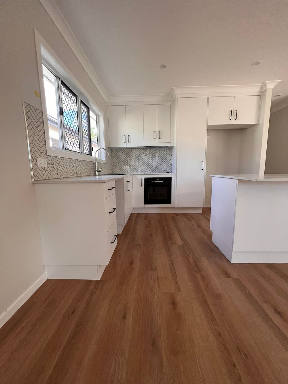 A White Kitchen With Wooden Flooring, and a Countertop — AGM Flooring & Tiling in Hidden Valley, QLD