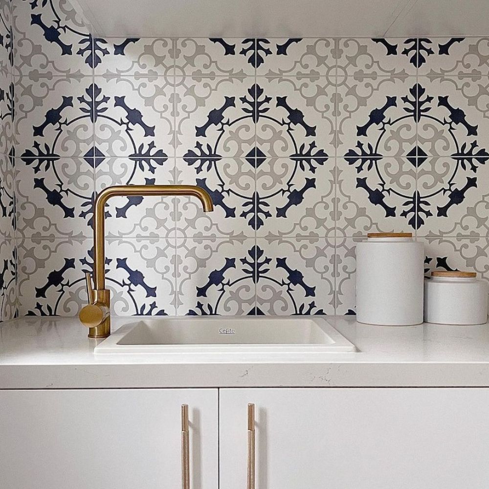 A White Sink With Gold Faucet Against Patterned Blue and Grey Tiles — AGM Flooring & Tiling in Hidden Valley, QLD
