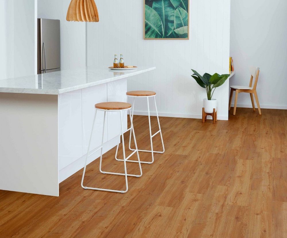 A Bright Kitchen With Wood-look Flooring, a White Counter With Stools — AGM Flooring & Tiling in Hidden Valley, QLD