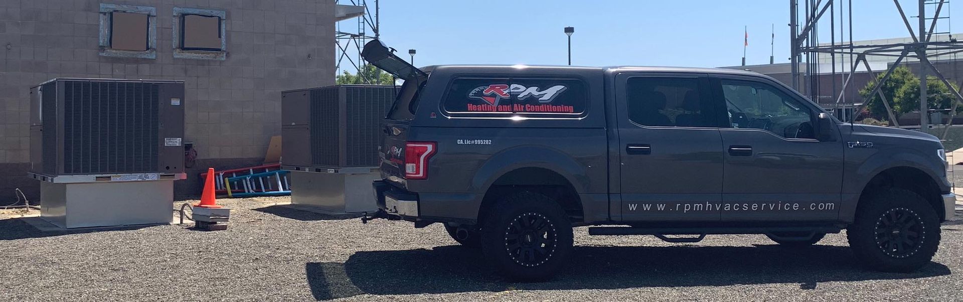 RPM HVAC service truck parked near two large rooftop HVAC units at a commercial site.