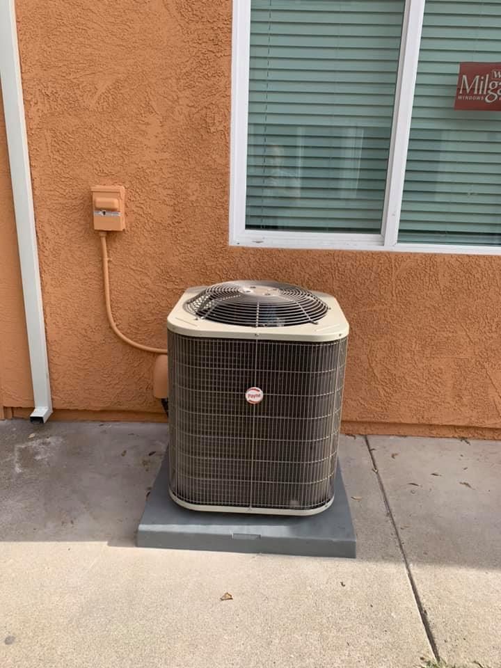 Payne AC condenser unit outside stucco home.
