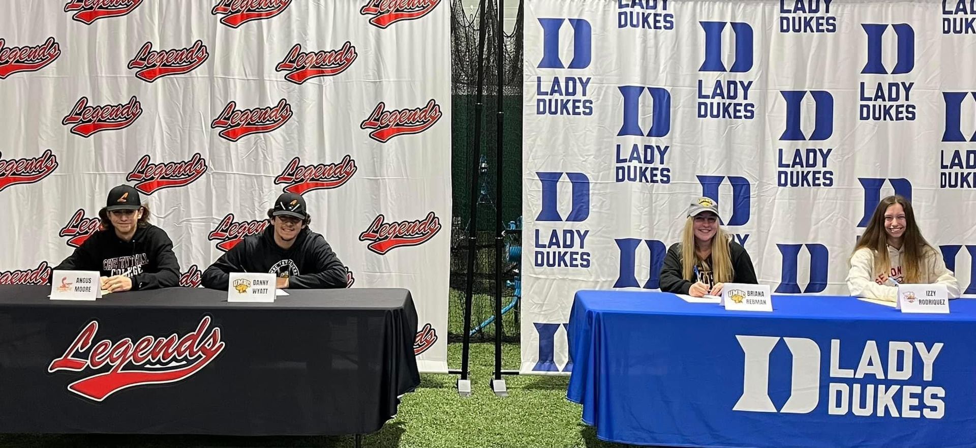 A group of people are sitting at tables in front of a Lady Dukes backdrop — Elkton, MD — Maryland Legends Baseball