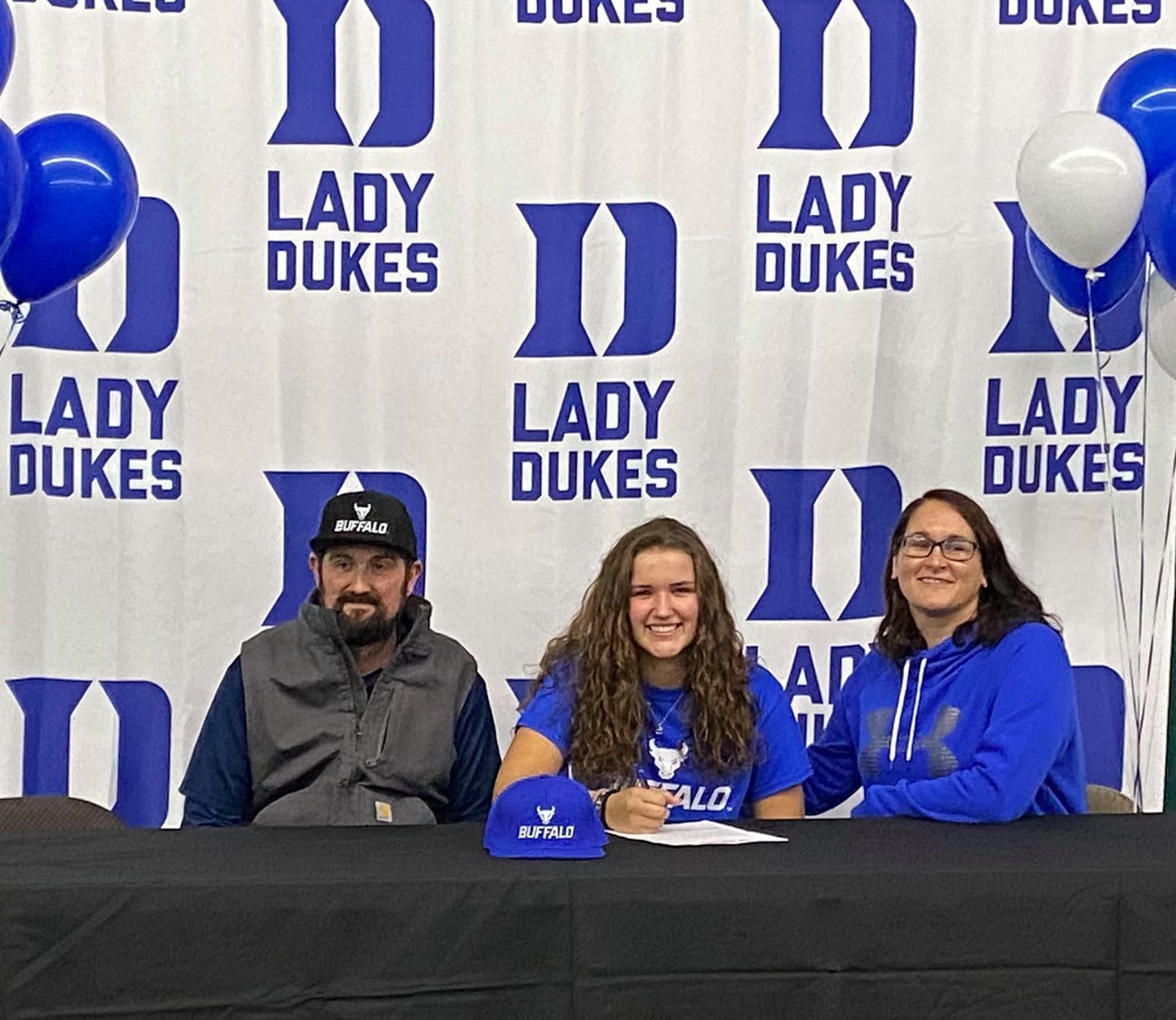 A man and two ladies are sitting at a table in front of a Lady Dukes banner — Elkton, MD — Maryland Legends Baseball