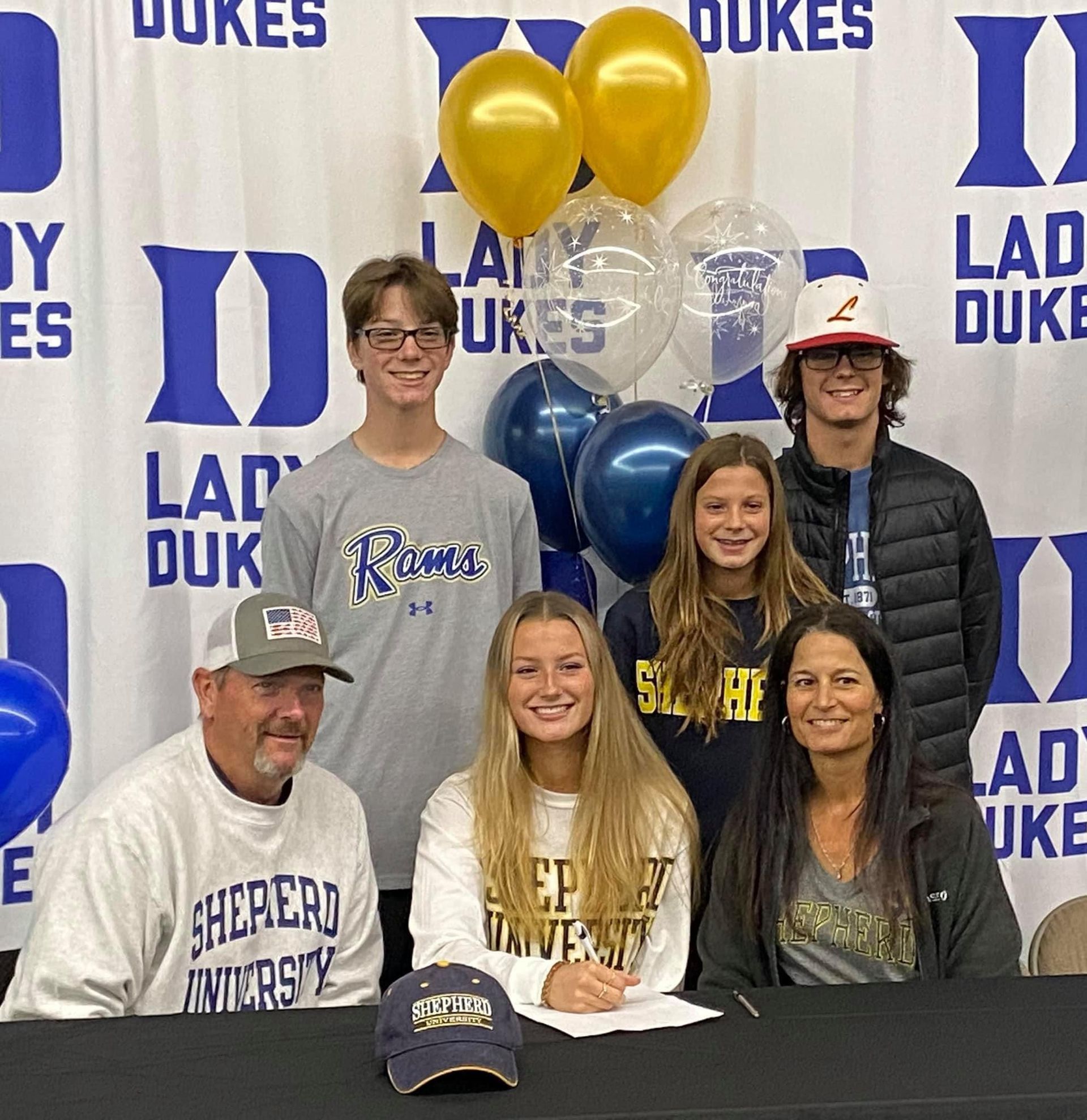 A group of people are sitting at a table in front of a Lady Dukes banner — Elkton, MD — Maryland Legends Baseball