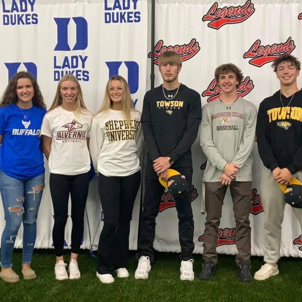 A group of people standing in front of a Lady Duke banner — Elkton, MD — Maryland Legends Baseball
