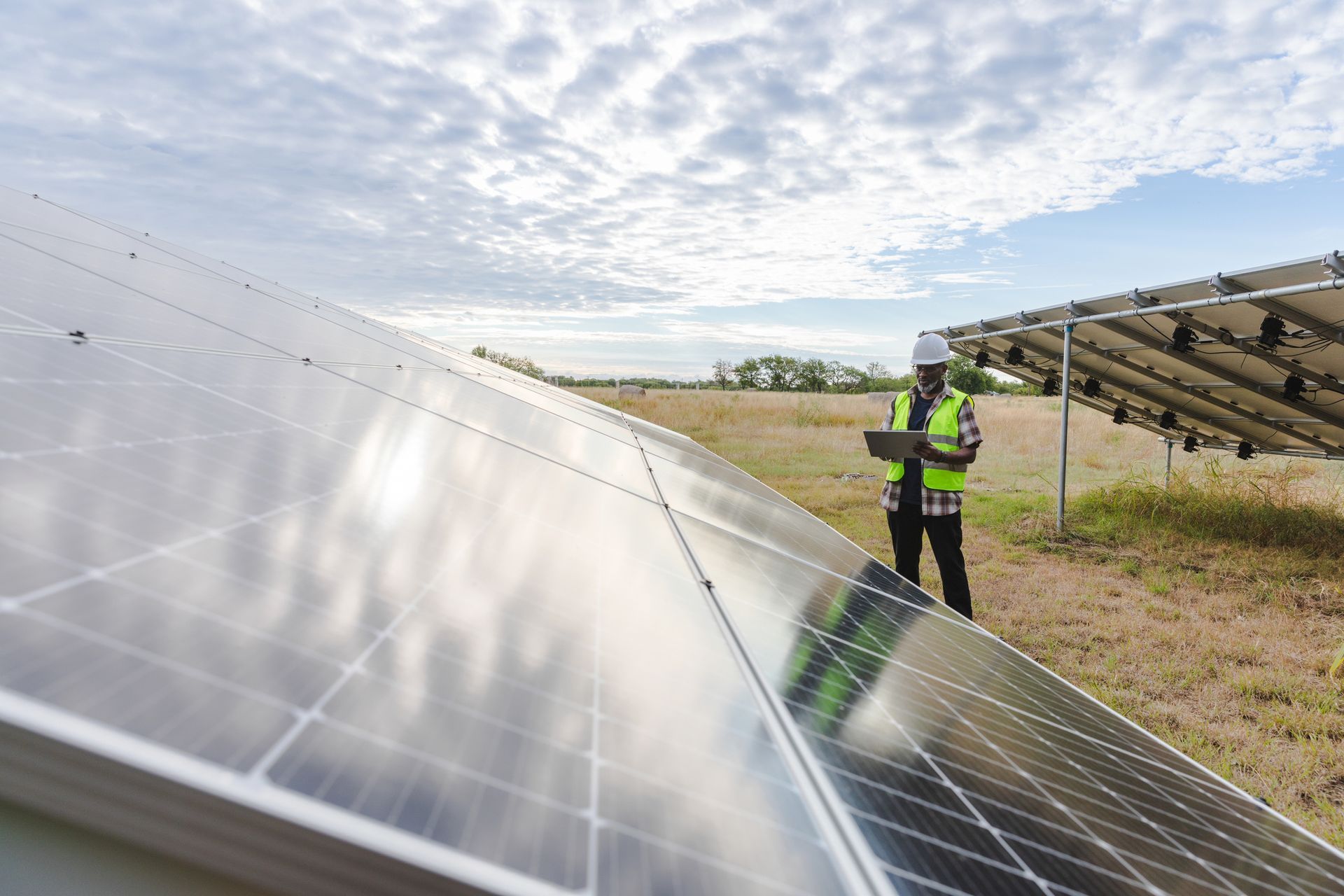 A man is standing in front of a field of solar panels.