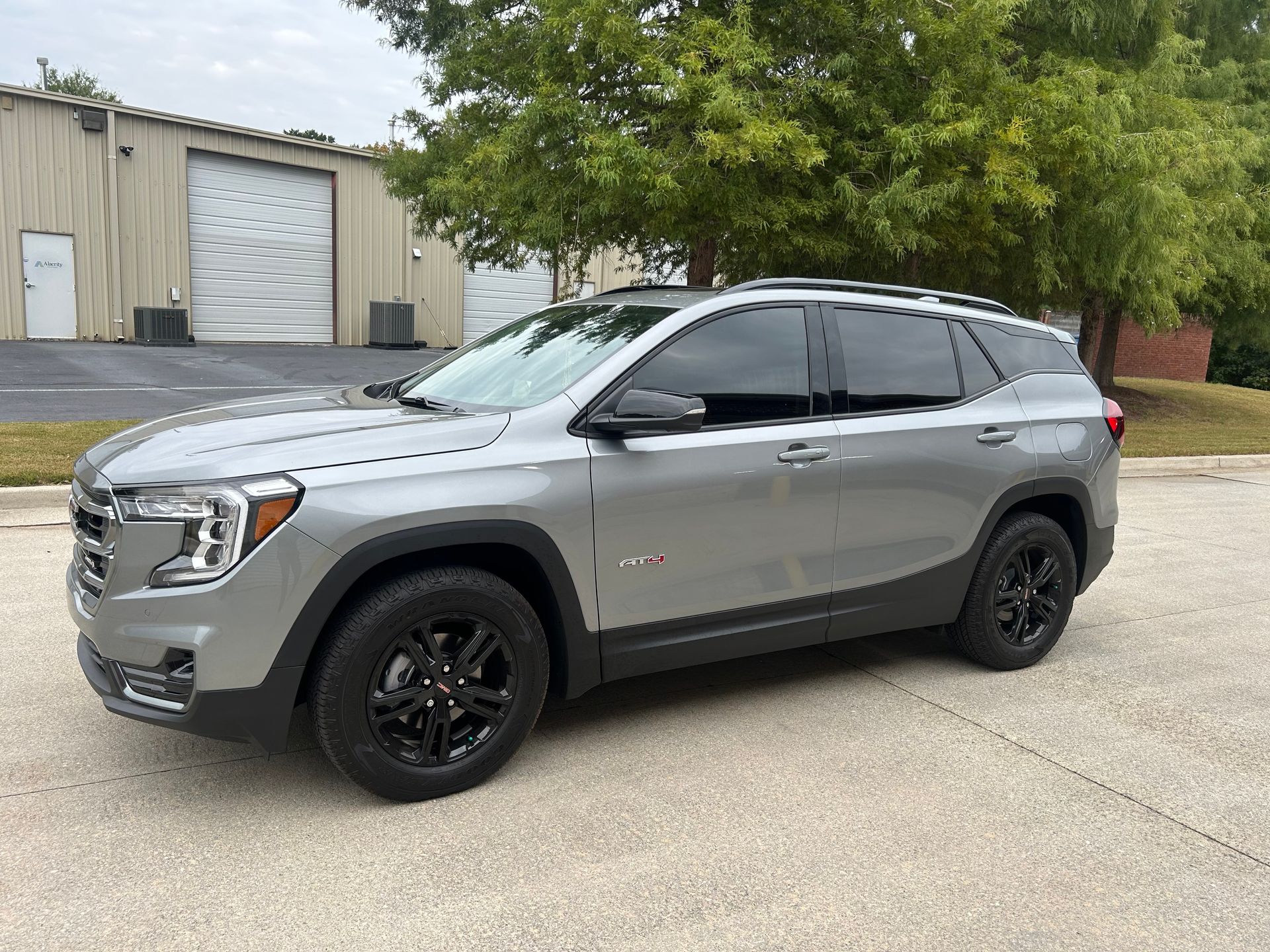 A gray gmc terrain is parked on the side of the road in front of a building.