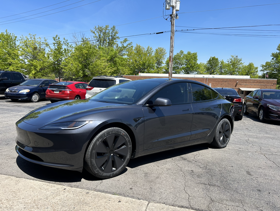 A black suv is parked in a parking lot in front of a brick building.