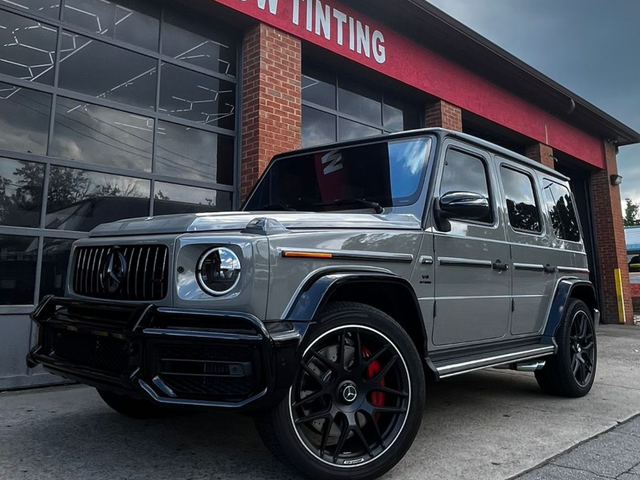 A black tesla model y is parked in front of a brick building.