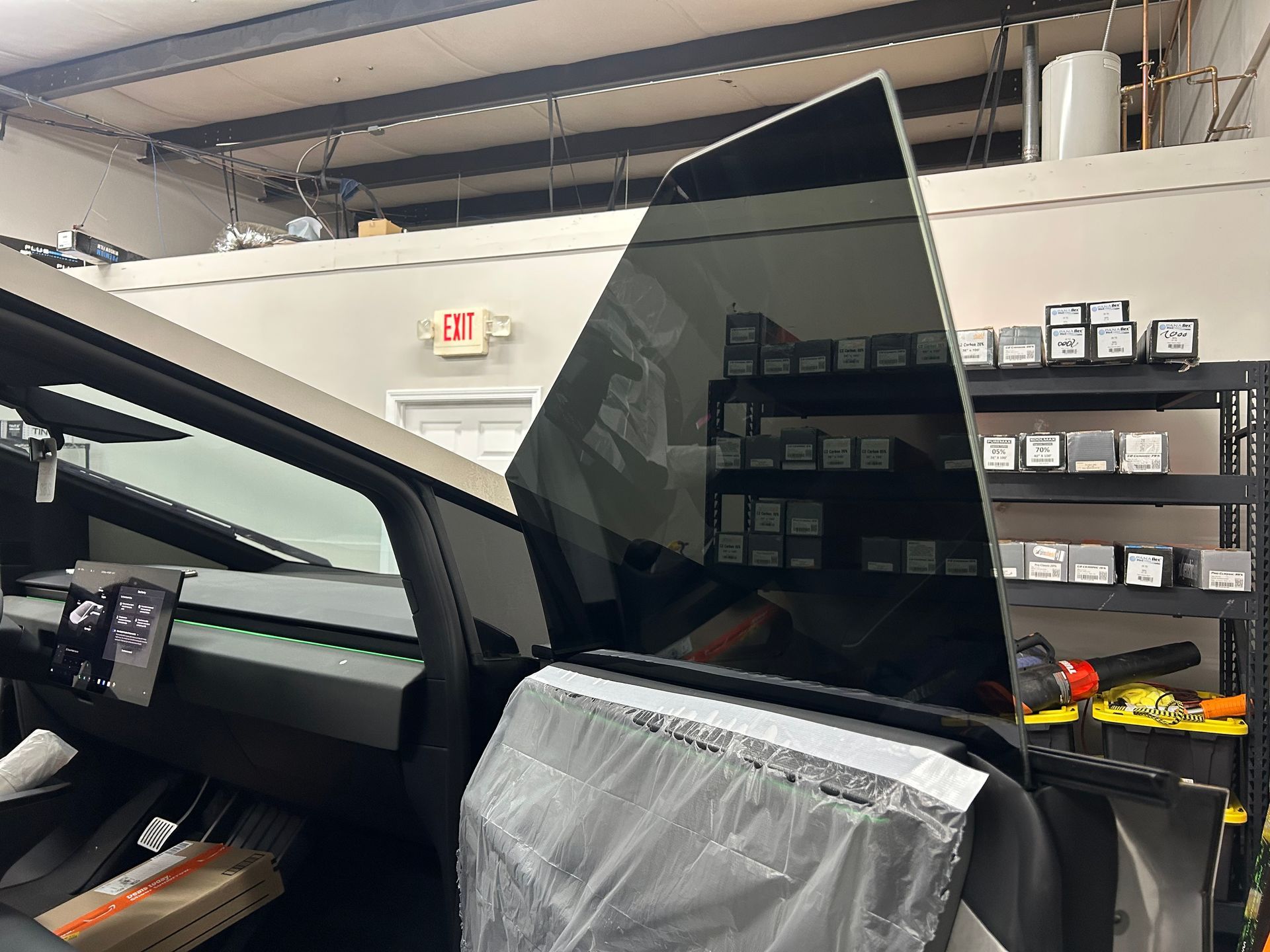 A tesla model 3 is sitting in a garage with its window open.