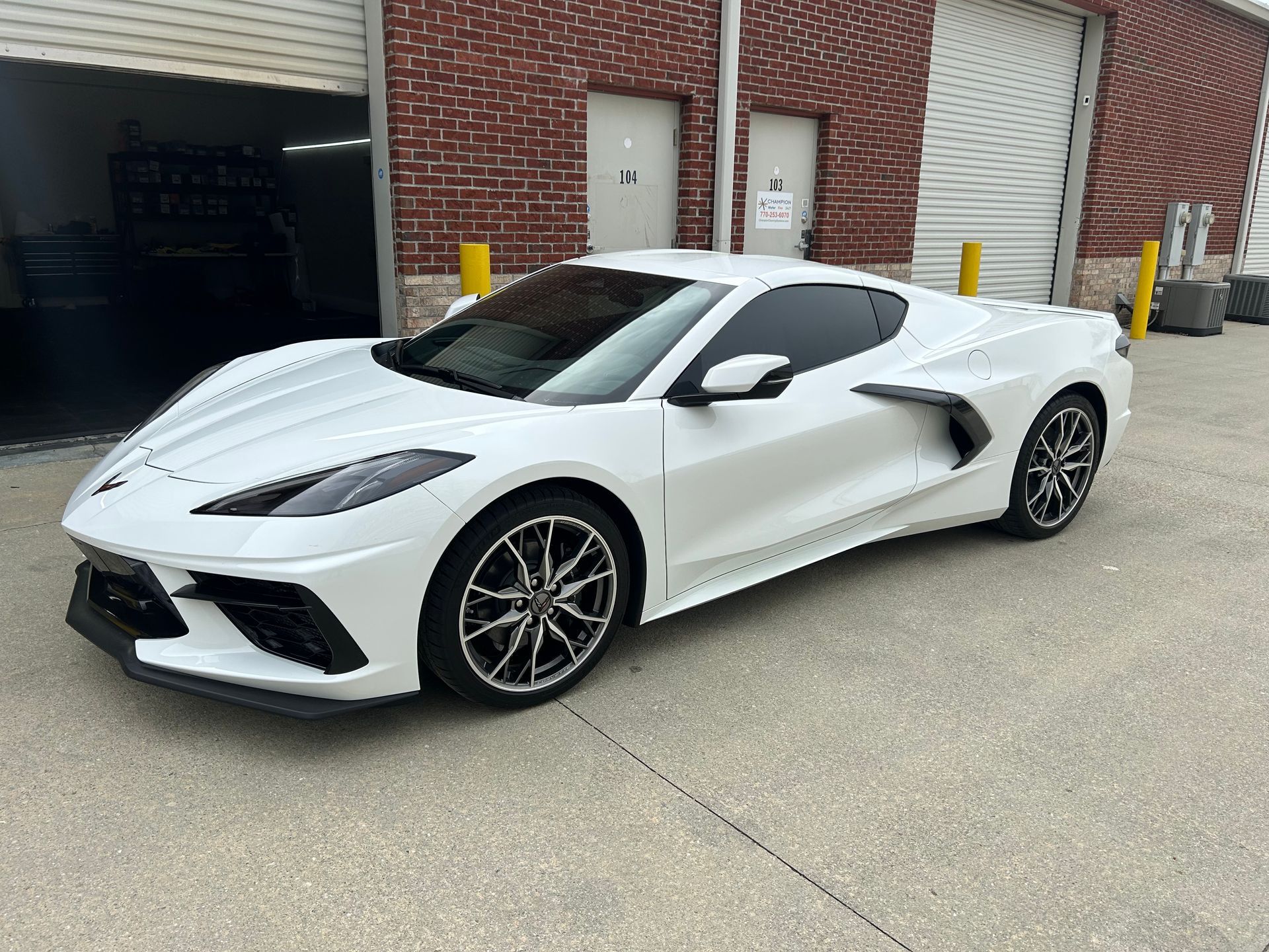 A white sports car is parked in front of a brick building.