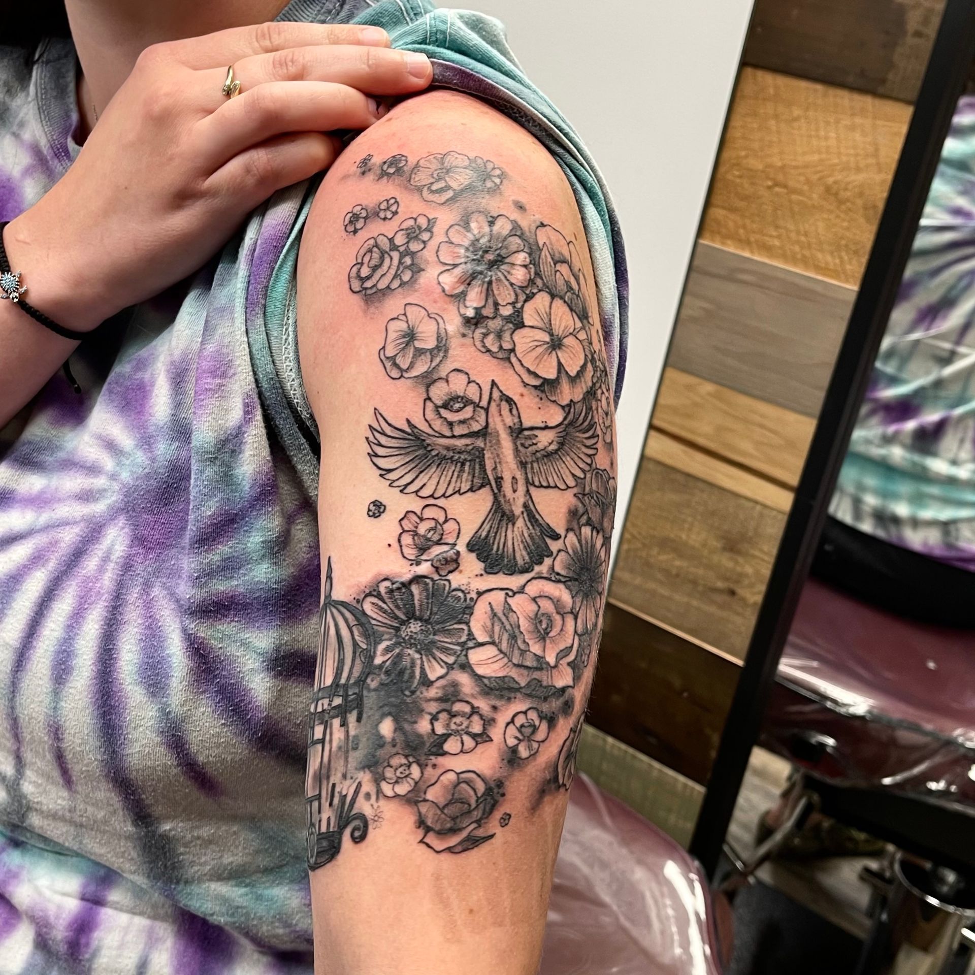 Bird with birdcage and flowers tattoo on upper arm