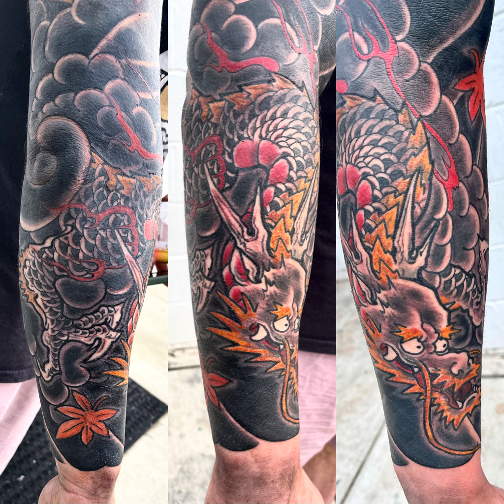 Black, red and yellow dragon in heavy wind sleeve tattoo