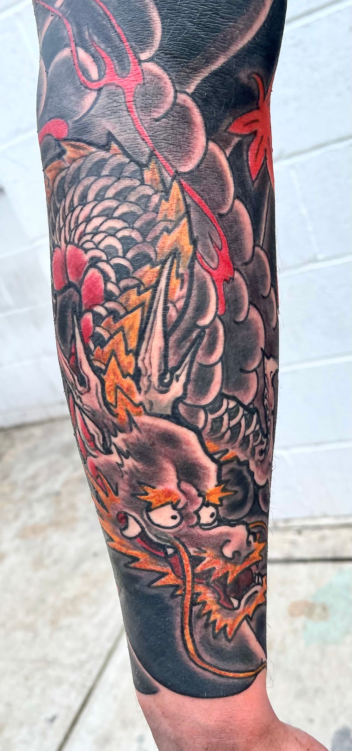Black, red and yellow dragon in heavy wind tattoo