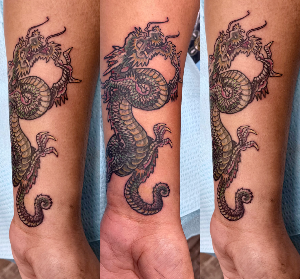 Small olive dragon tattoo on lower arm