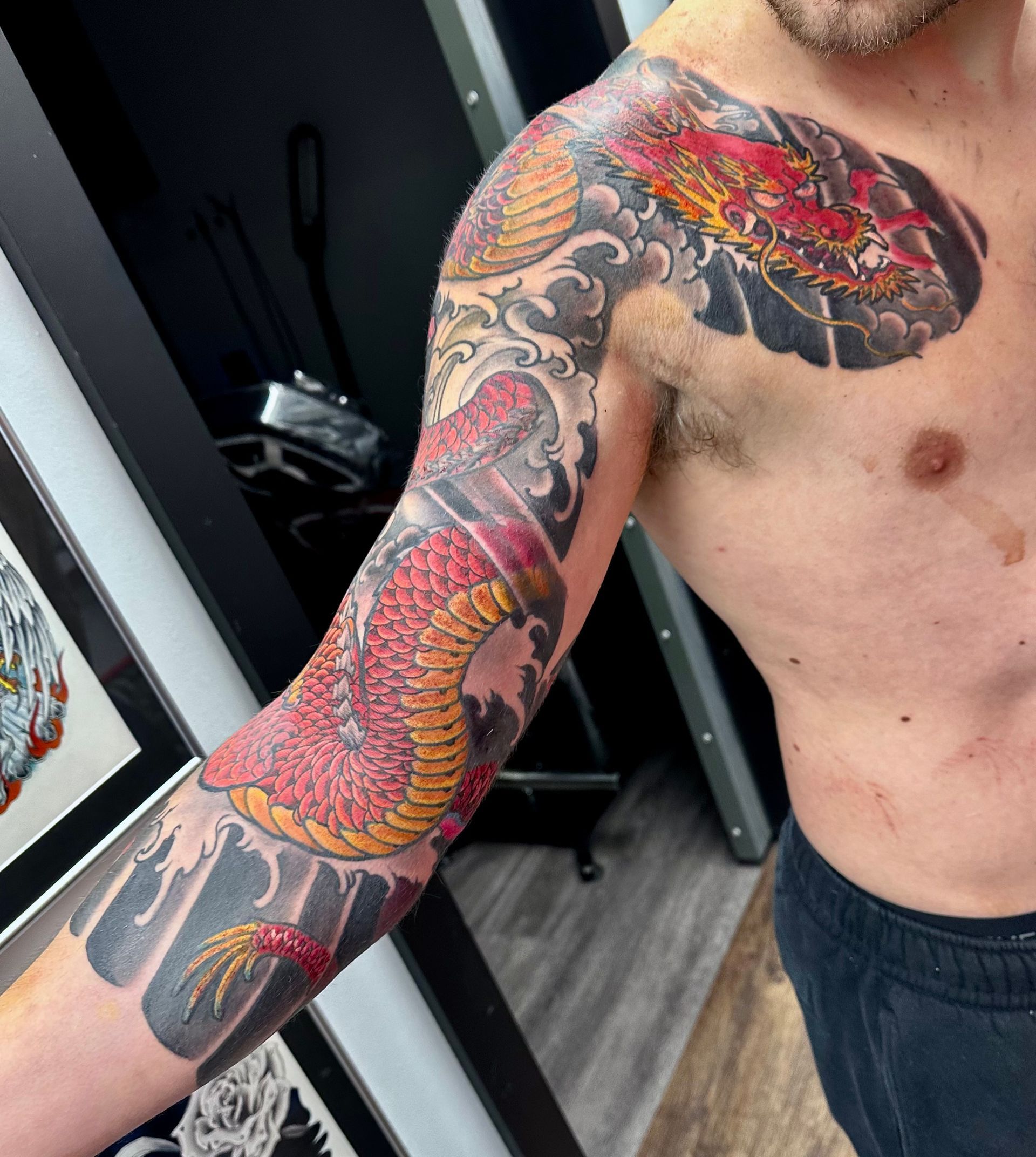 Red dragon in waves tattoo on shoulder and arm