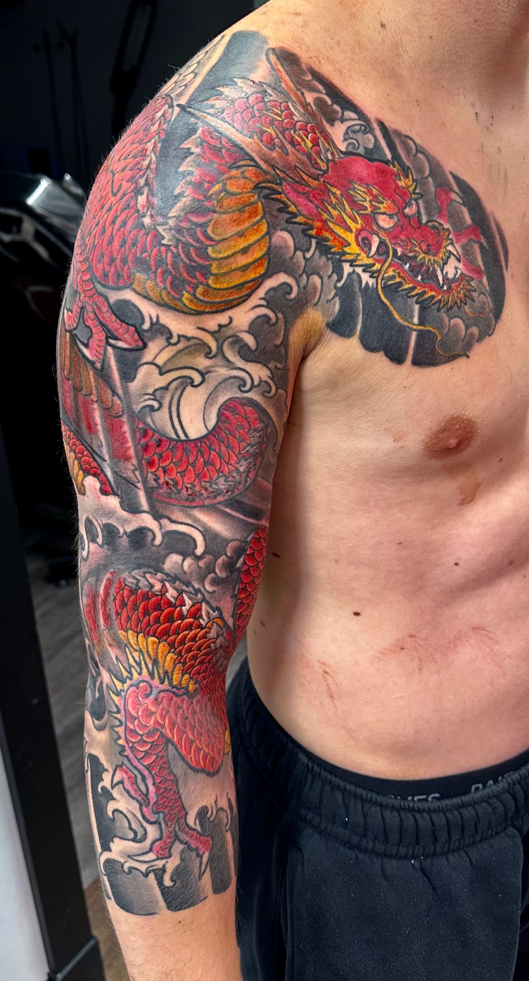 Red dragon in waves sleeve tattoo