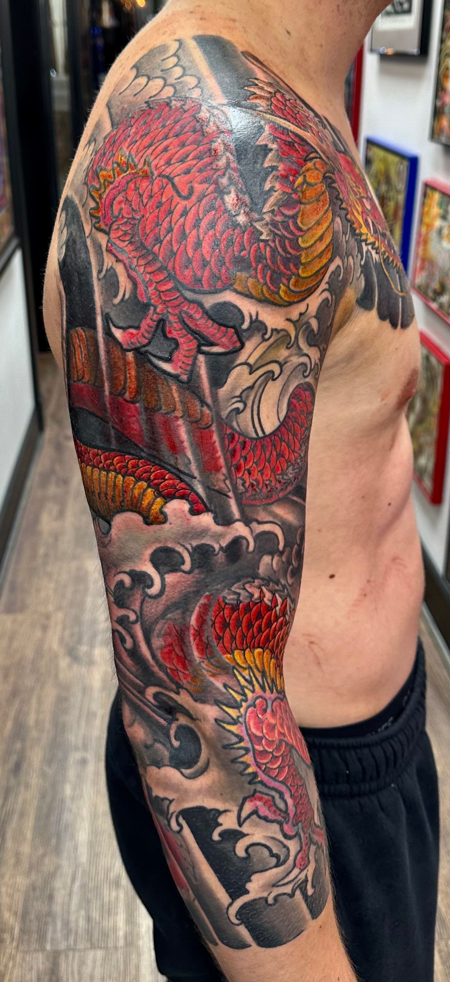 Red dragon in waves sleeve tattoo