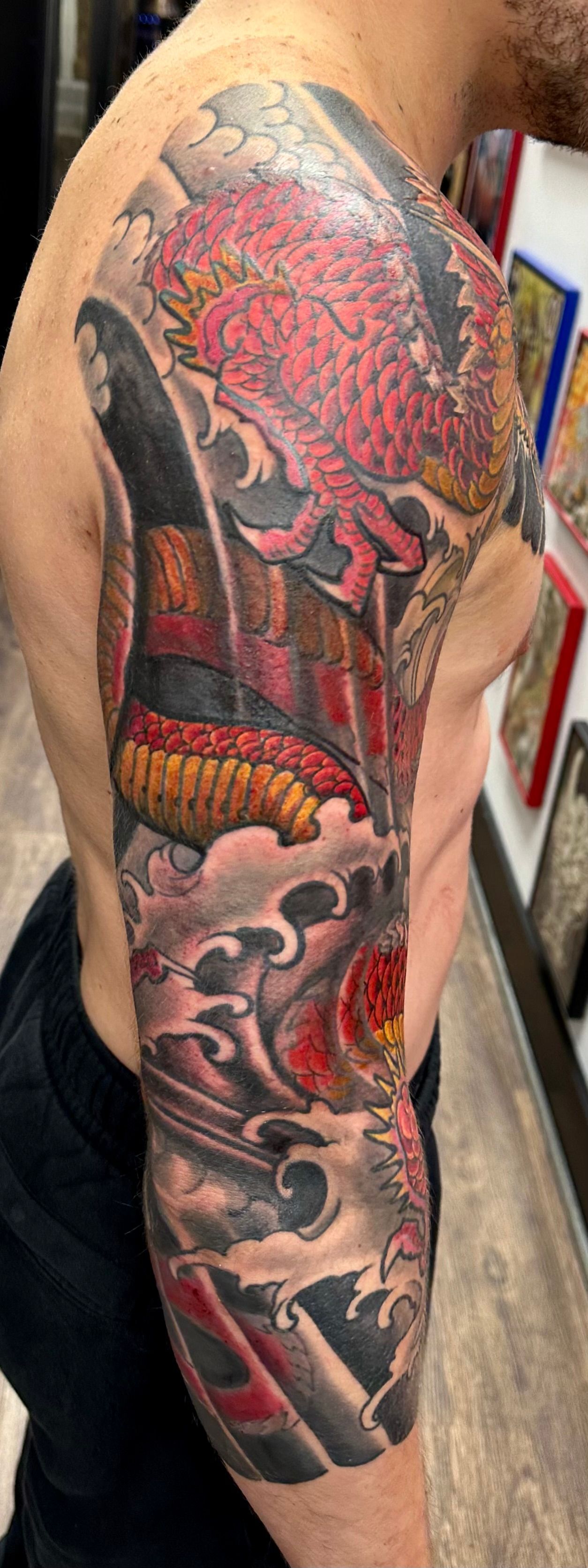 Red dragon in waves sleeve tattoo