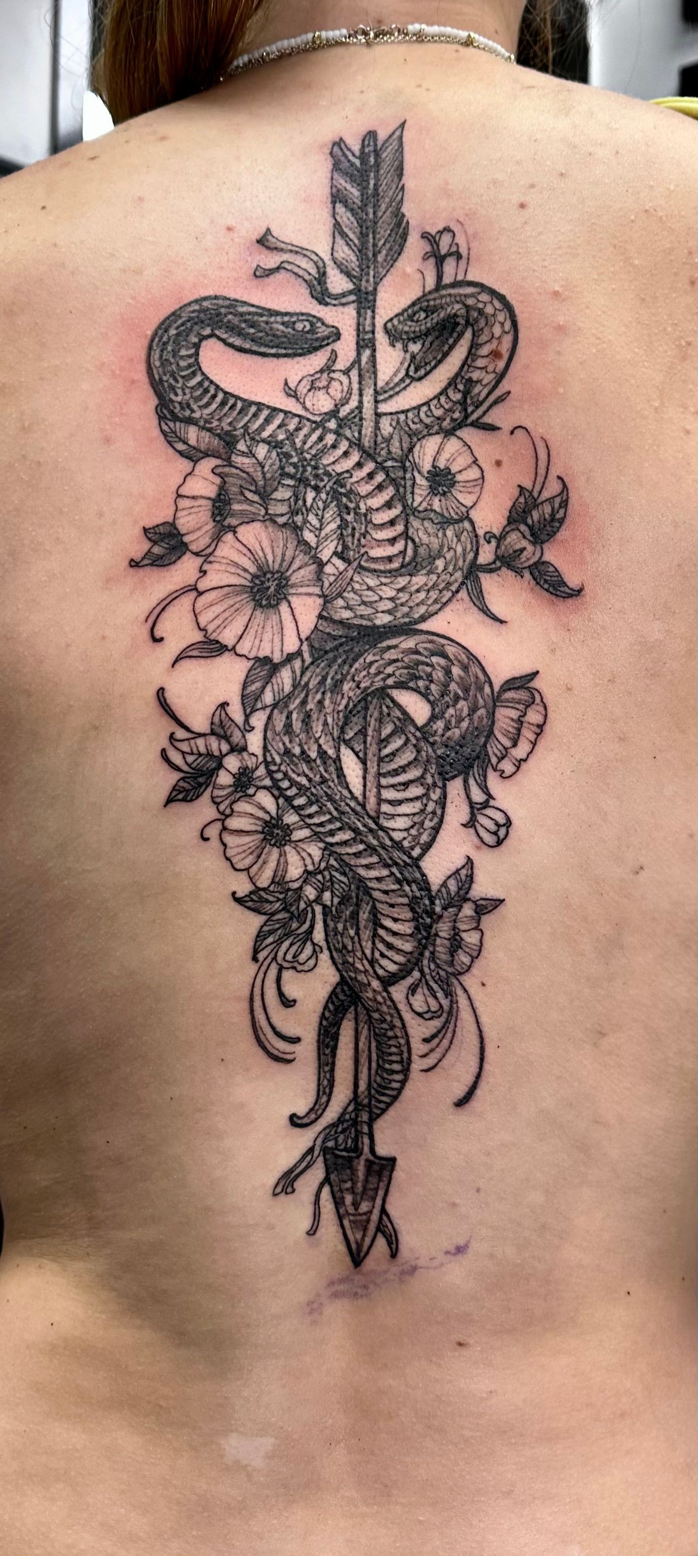 Snake with arrow and flowers tattoo