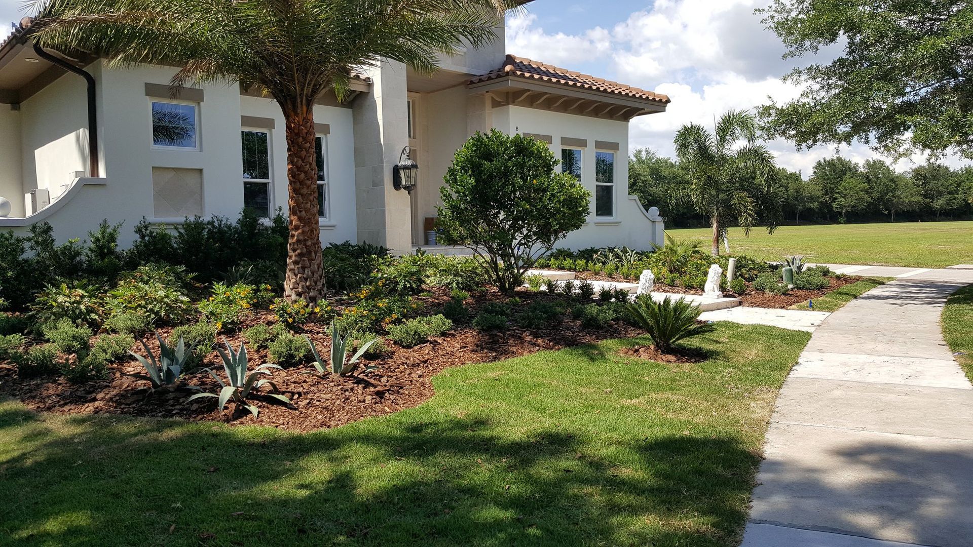 A house with a landscaped front yard and sidewalk on a sunny day.
