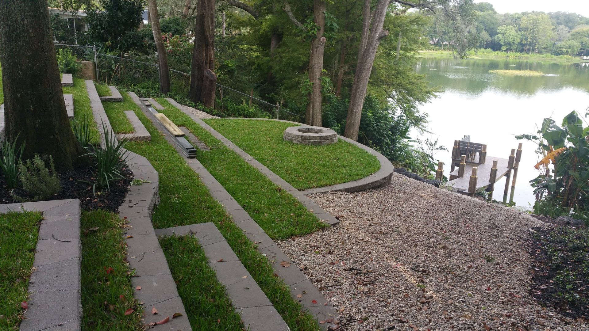 Landscaped waterfront with steps, grass, gravel, and a dock.