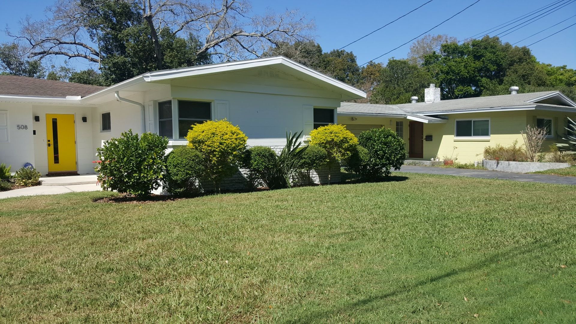 Lawn mowed in alternating stripes of light and dark green, curving towards a tree line.