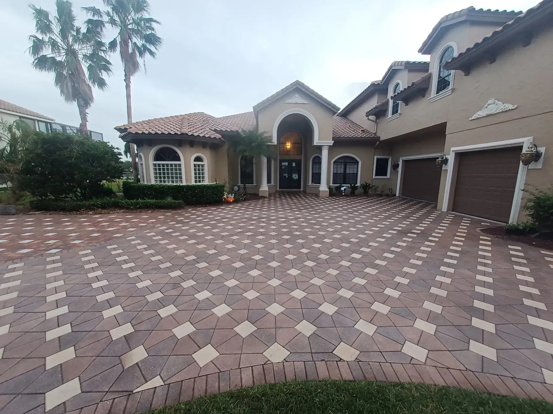White truck and two yellow riding lawnmowers parked on asphalt next to a garage.