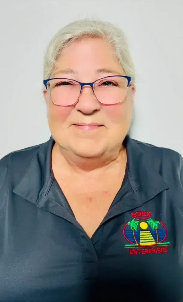 Woman with glasses in a gray shirt with a colorful logo, smiling, indoors.