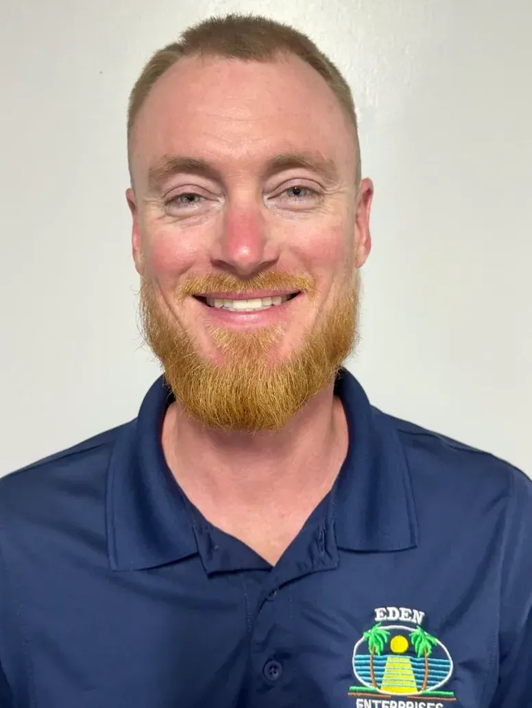 Man with a reddish-gold beard wearing a blue polo shirt, smiling at the camera.
