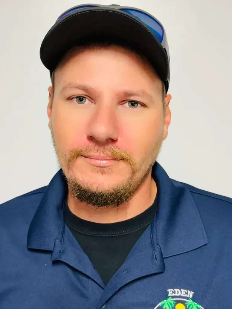 Man wearing a baseball cap and blue shirt, looking at the camera.