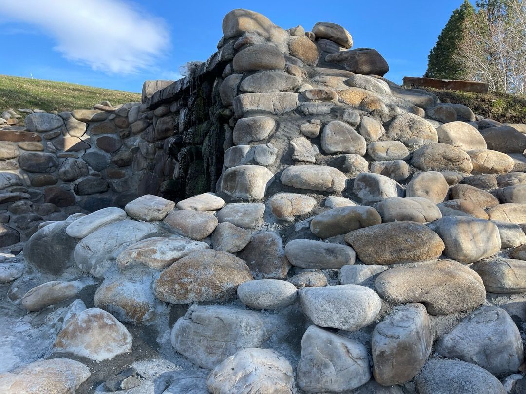 Stone structure with cascading water. Clear blue sky.