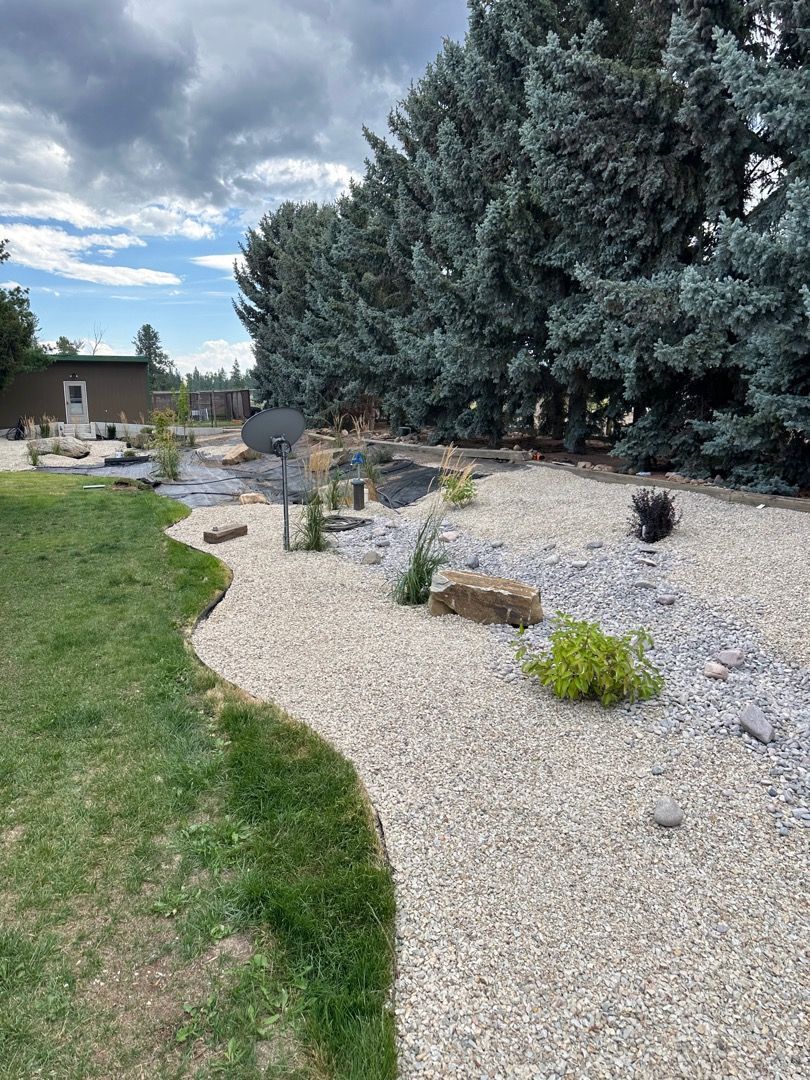 A backyard with a gravel pathway, lined with trees and greenery.