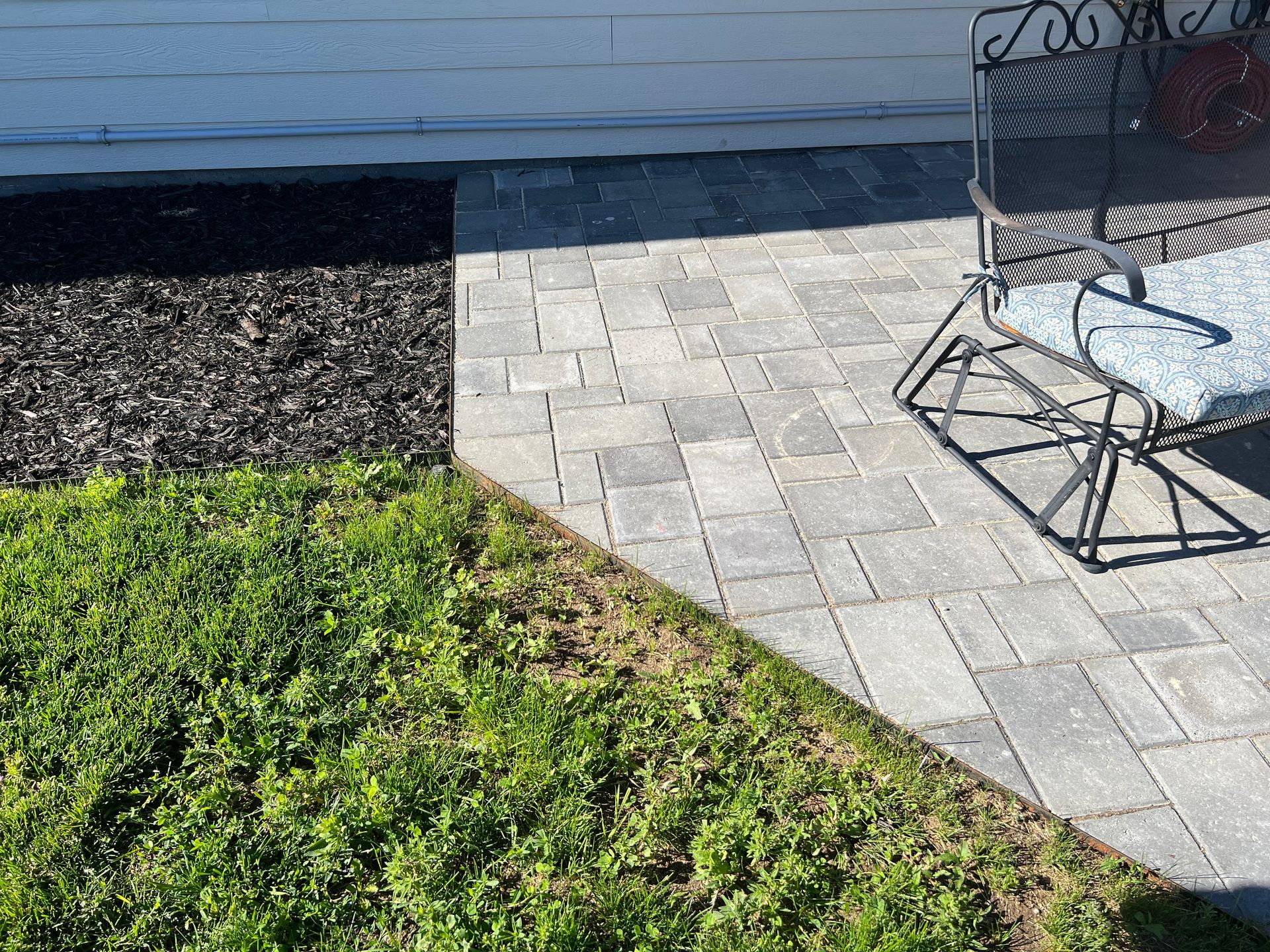 Brown wooden house with porch and landscaping; grass, mulch, and trees.