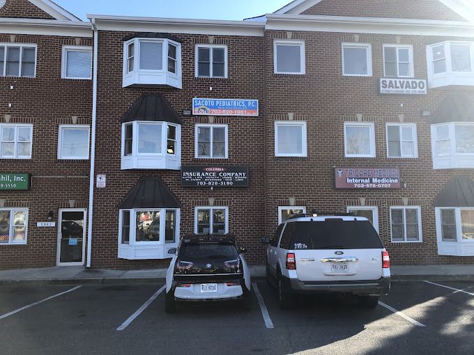 Two cars are parked in front of a brick building.