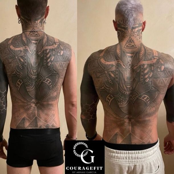 A man has a tattoo on his back that says couragefit