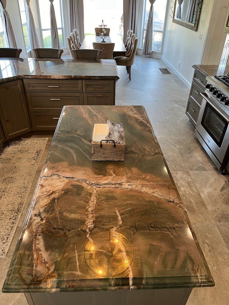 A kitchen with a large island with a marble counter top.