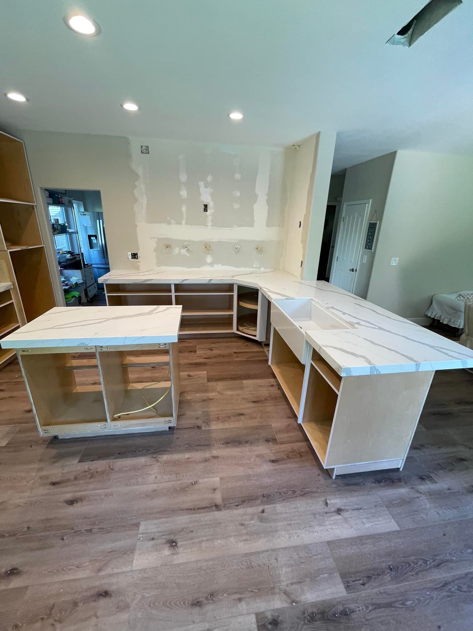 Kitchen under renovation; cabinets with countertops, unfinished walls, and wood flooring.
