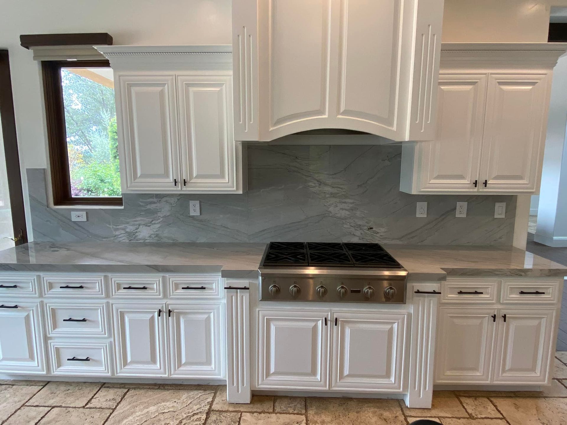 A kitchen with white cabinets and a stove top oven.